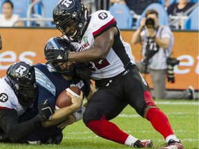 Toronto Argonauts quarterback McLeod Bethel-Thompson (14) is stopped by Ottawa Redblacks linebacker Avery Williams (42) during second quarter CFL action in Toronto on Thursday, August, 2, 2018.