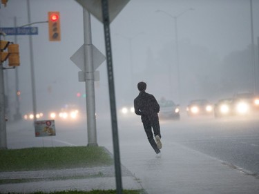 A pedestrian races along March Road as a reported tornado touched down in Dunrobin in the far west end of Ottawa.