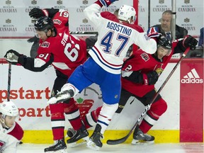 The Montreal Canadiens' Kenny Agostino collides with the Ottawa Senators' Mark Stone, left, and defenceman Dylan DeMelo along the boards.