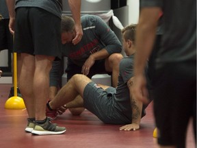 Ottawa Senators' Jean-Gabriel Pageau sits on the ground as a staff member looks at his right ankle during the first day of hockey training camp in Ottawa on Thursday, Sept. 13, 2018.
