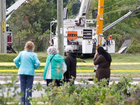 Pedestrians stop to watch hydro workers repair lines along Greenbank Rd and the east/ west hydro corridor running through Craig Henry.