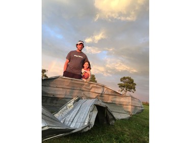 Andrew Mactaggart and his daughter Kristen, 8, in front of metal ripped from a barn several hundred metres from their home on Donald B Munro, near Kinburn. Joanne Laucius, Postmedia