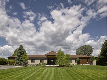 The renovated home looks like a lavish estate with beautiful landscaping, wooden detailing and a new circular driveway.