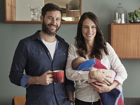 In this Aug. 1, 2018 photo New Zealand Prime Minister Jacinda Ardern, right, poses for a family portrait with partner Clarke Gayford and their baby daughter Neve in their home in Auckland, New Zealand.
