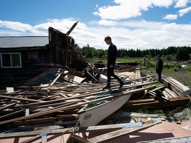 Kyle Tully walks along beams from a barn that was destroyed by a tornado at his home on his cousin Christine Earle's farm, as his boyfriend Colt Webber looks on, in Dunrobin, Ont.