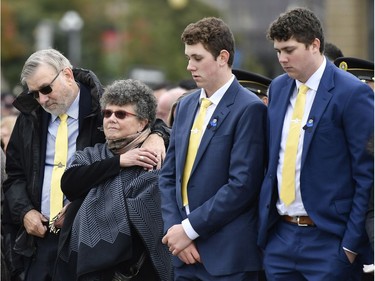 Marjorie Pirie, mother of Fredericton Police Const. Sara Burns, holds the hand of her husband, David Pirie, as they stand with grandsons Malcolm and Duncan Burns, right, during the Canadian Police and Peace Officers' Memorial Service on Sunday. Const/ Sara Burns was killed in a shooting in Fredericton on Aug. 10.