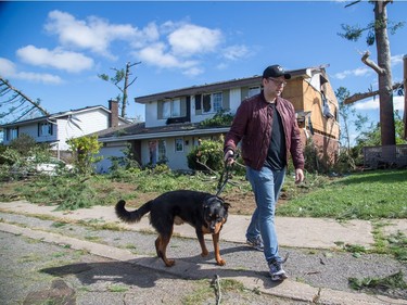 Ian MacArthur with his dog "Buddy" outside his damaged home on Riverbrook Rd in the Arlington Woods neighbourhood on Saturday morning as residents in Ottawa's west end deal with the aftermath of the twister that touched down on Friday afternoon.