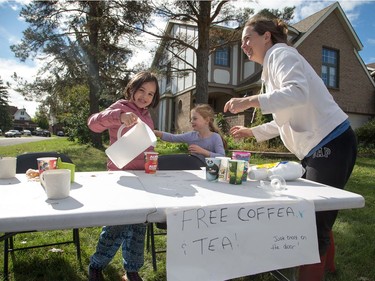 Good samaritans Alison Hurleigh with her daughter Jasmine Mackinnon, 7, (C) and friend Emma Lawrie(L), 8, on Saturday morning as residents in Ottawa's west end deal with the aftermath of the twister that touched down on Friday afternoon. Alison owns a generator which enabled them to make coffee. Photo by Wayne Cuddington/ Postmedia