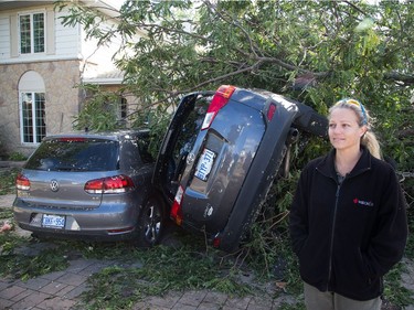 Renata Scorsone stands outside her home on Conover St on Saturday morning where her two vehicles were damaged as residents in Ottawa's west end deal with the aftermath of the twister that touched down on Friday afternoon.
