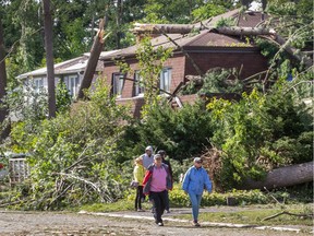People walk about the Arlington Woods neighbourhood on Saturday morning as residents in Ottawa's west end deal with the aftermath of the twister that touched down on Friday afternoon.