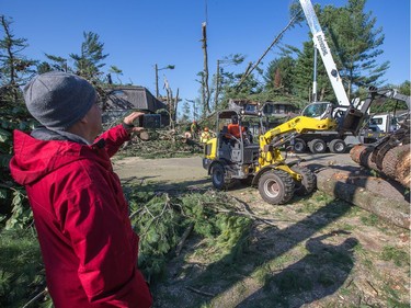 Tom Schnarr takes video of crews removing trees from his home on Parkland Cres in Arlington Woods as the region continues to deal with the after effects of the tornados that struck the region on Friday.