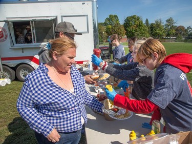 Kristy Rubino gets some mustard squeezed on her burger by volunteer Darcy Titcombe, 14, at the Margaret Rywack Communtiy Centre in Manordale, a free lunch organized by the city as the region continues to deal with the after effects of the tornados that struck the region on Friday