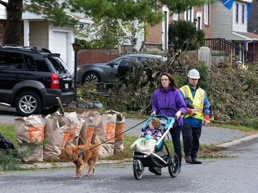 A woman walks past branches and other debris collected in Craig Henry on Saturday. Wayne Cuddington/Postmedia