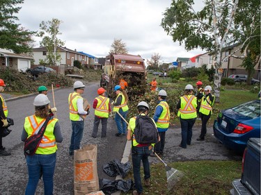 An army of volunteers helps clear brush from properties along Elvaston Drive on Saturday. Wayne Cuddington/Postmedia