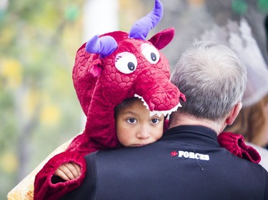 Six-year-old Arielle Villeneuve, wearing her dragon costume, gets a lift during Trick or Treat with the Mayor on Saturday.   Ashley Fraser/Postmedia