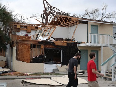 PANAMA CITY, FL - OCTOBER 11:  People walk past an apartment destroyed by Hurricane Michael on October 11, 2018 in Panama City, Florida. The hurricane hit the Florida Panhandle as a category 4 storm.