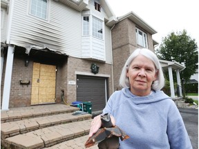 Vicky Earl stands next to her neighbour's house, which caught fire in July. Earl's house is the one on the right.