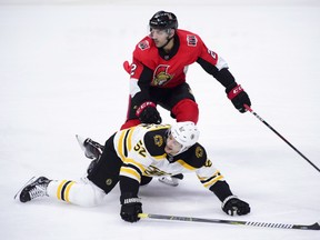 Ottawa Senators defenceman Dylan DeMelo pushes Boston Bruins centre Sean Kuraly to the ice during Tuesday's game. (THE CANADIAN PRESS)
