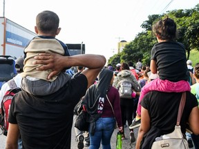 Two honduran kids are carried by two adults during an exodus towards the US from San Pedro Sula, 180 kms north from Tegucigalpa, on October 13, 2018. - Hondurans decided to left their country due to insecurity and the lack of employment opportunities. The exodus started from the bus terminal in San Pedro Sula towards the border with Guatemala.