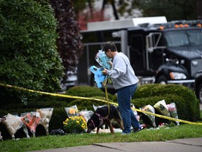 A woman leaves flowers at a memorial on October 28, 2018 outside the Tree of Life Synagogue after a shooting there left 11 people dead in the Squirrel Hill neighborhood of Pittsburgh on October 27, 2018. - A man suspected of bursting into a Pittsburgh synagogue during a baby-naming ceremony and gunning down 11 people has been charged with murder, in the deadliest anti-Semitic attack in recent US history. The suspect -- identified as a 46-year-old Robert Bowers -- reportedly yelled "All Jews must die" as he sprayed bullets into the Tree of Life synagogue during Sabbath services on Saturday before exchanging fire with police, in an attack that also wounded six people.