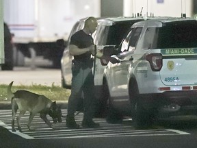 A police officer and dog are shown outside a postal facility, Thursday, Oct. 25, 2018, in Opa-locka, Fla.