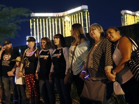 Survivors of a mass shooting form a human chain around the shuttered site of a country music festival on the first anniversary, Monday, Oct. 1, 2018, in Las Vegas.