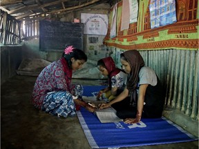 In this photo from Aug. 22, Rahima Akter, left, teaches her siblings inside the family hut in Kutupalong refugee camp in Bangladesh. Rahima is a 19-year-old refugee who dreams of becoming the most educated Rohingya woman in the world.