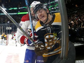 In this photo taken with a fisheye lens, Boston Bruins' Ryan Donato, front, is checked into the boards by Montreal Canadiens' Nicolas Deslauriers during the first period of an NHL hockey game Saturday, Oct. 27, 2018, in Boston.