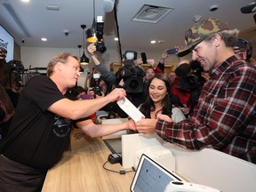 Canopy Growth CEO Bruce Linton, left to right, provides the receipt for the first legal cannabis for recreation use sold in Canada to Nikki Rose and Ian Power at the Tweed shop on Water Street in St. John's N.L. at 12:01 am NDT on Wednesday October 17, 2018.