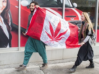 People hold up a Canadian flag with a marijuana logo on it outside a government cannabis store in Montreal, Wednesday, October 17, 2018.