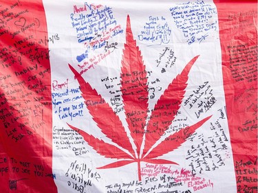 People hold up a Canadian flag with a marijuana logo on it outside a government cannabis store in Montreal, Wednesday, October 17, 2018.