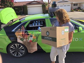 Customer Maureen Blaskovich grabs a coconut water from the backseat window of a self-driving car, a Lincoln MKZ outfitted with technology by AutoX, in San Jose, Calif. on Aug. 29, 2018. Internal government documents show that more than one million jobs could be lost to automated vehicles, with ripple effects far beyond the likeliest professions. A presentation federal officials put together last year predicts automation could kill some 500,000 transportation jobs, from truck drivers to subway operators to taxi drivers and even courier services, but doesn't put a timeline to the potential losses.