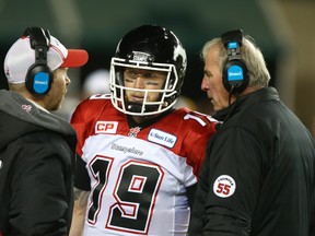 Stampeders quarterback Bo Levi Mitchell (centre) talks with offensive coach Dave Dickenson (left) and head coach John Hufnagel in 2015. Dickenson is now the head coach and Hufnagel is the general manager.  Jim Wells/Postmedia Network