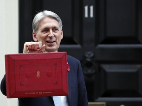 Britain's Chancellor of the Exchequer Philip Hammond poses for the media as he holds up the traditional red dispatch box, outside his official residence 11 Downing Street before delivering his annual budget speech to Parliament in London, Monday, Oct. 29, 2018.