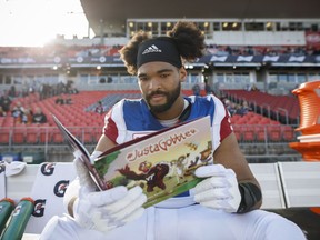 Montreal Alouettes defensive tackle Woody Baron (97) poses with his children's book on the sidelines in Toronto on Saturday, Oct. 20, 2018. Woody Baron finds the spectre of tangling with a hulking offensive lineman much less daunting than sitting before young children. The Montreal Alouettes rookie defensive lineman has co-authored a book entitled #JustaGobbler with his uncle, James Baron, and Henry Taylor. The 38-page hardcover publication was released in August for third- and fourth-graders.