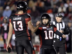 Holder Richie Leone (13) congratulates Redblacks kicker Lewis Ward (10) on his 40th consecutive field goal, breaking a CFL record, during the second half of Friday's game against the Blue Bombers.
