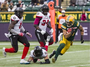 Edmonton Eskimos' Nate Behar (11) carries the ball under pressure from Ottawa Redblacks' Chris Ackie (5) Kyries Hebert (34) and Brendan Gillanders during second half CFL action in Edmonton on Saturday, Oct. 13, 2018.