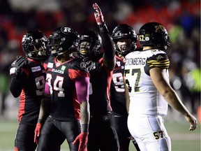 Ottawa Redblacks linebacker Kyries Hebert (34) celebrates a win with teammates as Hamilton Tiger-Cats offensive lineman Brandon Revenberg (57) leaves the field following the game at TD Place on Friday, Oct. 19, 2018.