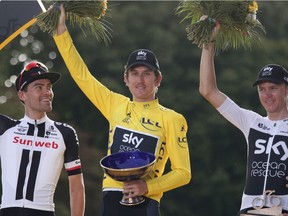 FILE - In this Sunday July 29, 2018 file picture, Tour de France winner Britain's Geraint Thomas, wearing the overall leader's yellow jersey, celebrates on the podium with Netherlands' Tom Dumoulin, left, who placed second, and Britain's Chris Froome, right, who placed third, on the Champs-Elysees avenue in Paris, France. The team said in a statement on Wednesday that police is investigating the case after the trophy disappeared during an event organized in Birmingham, where Team Sky displayed the three Grands Tours trophies won by its riders.