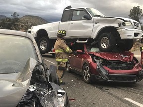 In this Sunday, Oct. 7, 2018 photo provided by the Prescott Fire Department, firefighters work the scene of an accident in Prescott, Ariz. Firefighters in Prescott said nobody was hurt after a pickup truck was hit by another car, went flying through the air and then landed on a third vehicle.