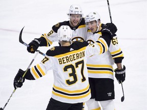 Bruins winger David Pastrnak, top, celebrates a third-period goal against the Senators with linemates Brad Marchand and Patrice Bergeron (37).