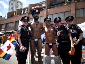 Revellers pose for a photos with police officers at the annual Pride Parade in Toronto on Sunday, July 3, 2016.