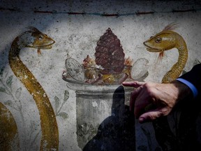 Massimo Osanna, the director of the Pompeii archaeological site, shows a fresco in a house discovered during excavation works in Pompeii, Italy, presented to journalists Friday, Oct. 5, 2018. Archaeologists excavating near Porta Vesuvio, in an unexplored part of Pompeii, have discovered a richly painted house with an "enchanted garden", with incredibly intact frescos and a majestic lararium, a shrine to the guardian spirits, one of the largest ever discovered in the city buried when Mt. Vesuvius erupted in 79 AD.