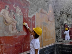 Archaeologists work on frescos during new excavations at the Pompeii archaeological site, Italy, Tuesday, Oct. 16, 2018. Archeologists have found writings proving that the famous 79 AD eruption happened two months later than what the scientific community currently believes.