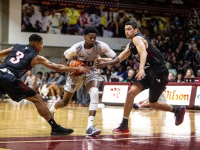 Ottawa’s Brandon Robinson tries to split Raven defenders T.J. Lall and Brandon Robinson during Carleton’s blowout win in their OUA men’s basketball opener last night on Friday at Montpetit Hall. The Ravens won 86-69. (Liam Mahoney)