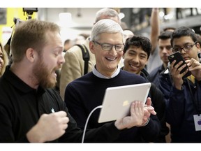 FILE- In this March 27, 2018, file photo Apple CEO Tim Cook smiles as he watches a demonstration on an iPad at an Apple educational event at Lane Technical College Prep High School in Chicago. New iPads and Mac computers are expected Tuesday, Oct. 30, as part of an Apple event in New York.