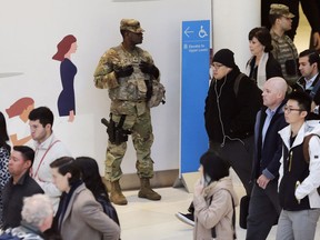A member of the New York National Guard, center, watches as commuters walk through the World Trade Center Transportation Hub, Thursday, Oct. 25, 2018, in New York. A series of pipe bombs sent to prominent Democrats including Barack Obama and Hillary Clinton has deepened political tensions and fears two weeks before national midterm elections.