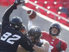 Redblacks quarterback Trevor Harris looks past the outstretched arm of defensive lineman George Uko while attempting a pass during practice at TD Place stadium on Tuesday.   Tony Caldwell/Postmedia