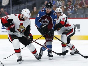 Colorado Avalanche right wing Mikko Rantanen, center, loses control of the puck while driving to the net between Ottawa Senators left wing Tom Pyatt, left, and defenseman Cody Ceci in the third period of an NHL hockey game Friday, Oct. 26, 2018, in Denver. The Avalanche won 6-3.