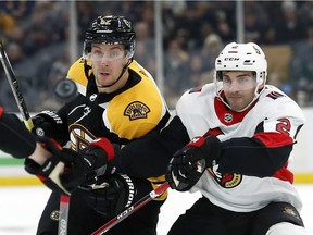 The Bruins' Sean Kuraly, left, and the Senators' Dylan DeMelo eye a loose puck as it flies in front of them during the second period of Monday's game in Boston.